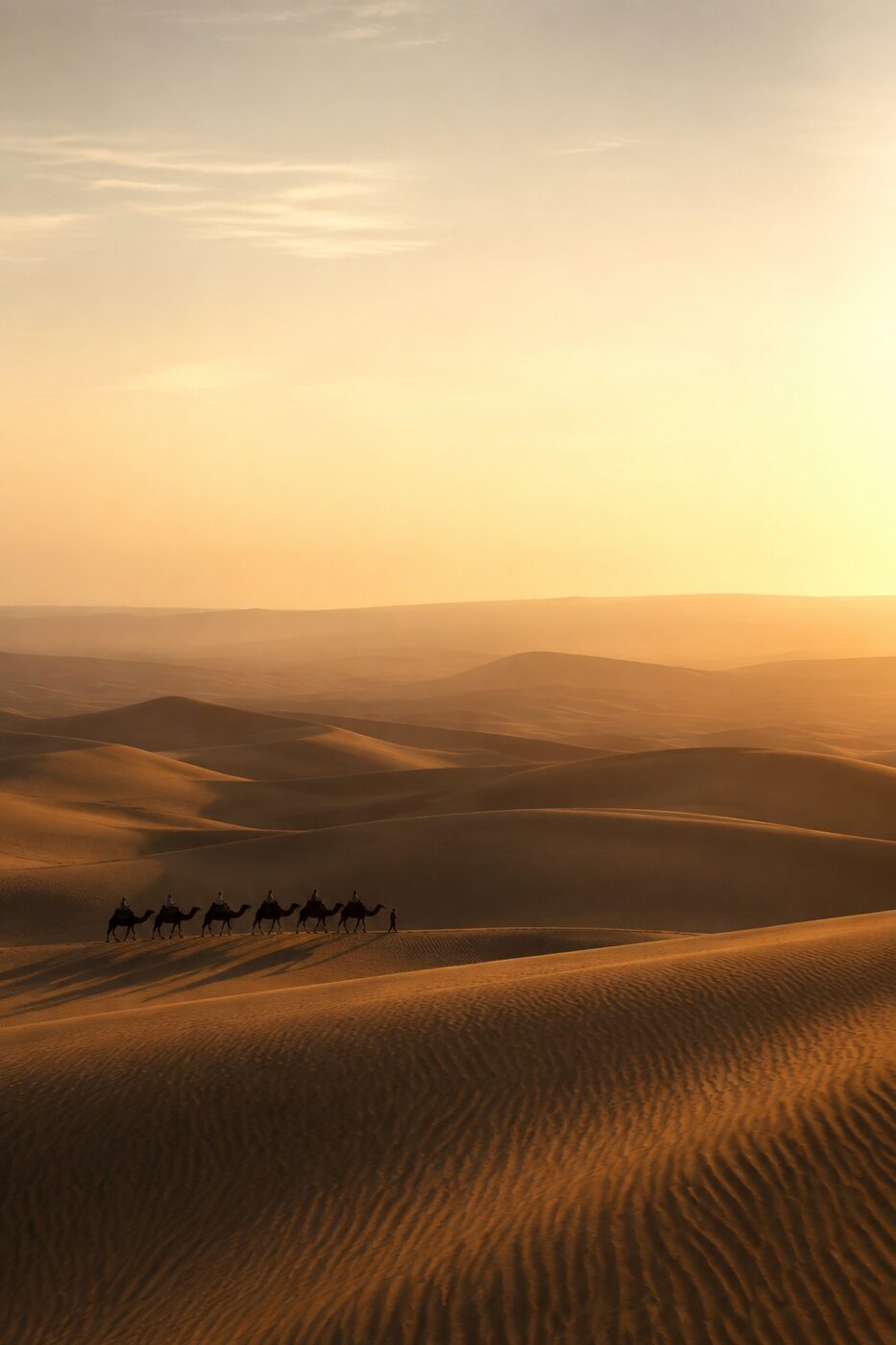 A distant caravan crossing dunes at golden hour